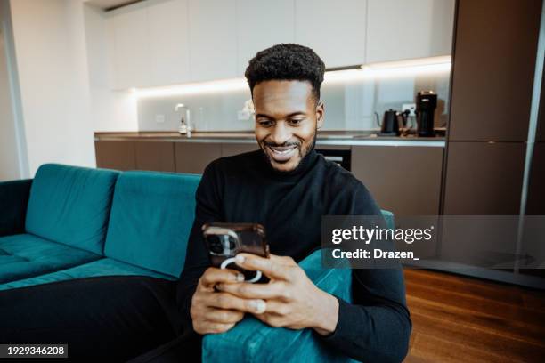 afro-caribbean mid adult man using smart phone in modern office or apartment - afro caribbean portrait stock pictures, royalty-free photos & images