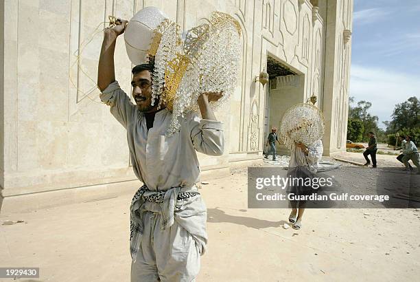 Looters run off with chandeliers from a Palace April 11, 2003 Baghdad, Iraq. Baghdad, the Iraqi capital is still reeling from widespread looting and...