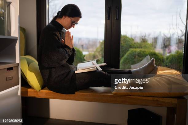 woman praying at home - trust god stock pictures, royalty-free photos & images