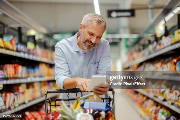 one mature man in supermarket - shopping list stock pictures, royalty-free photos & images