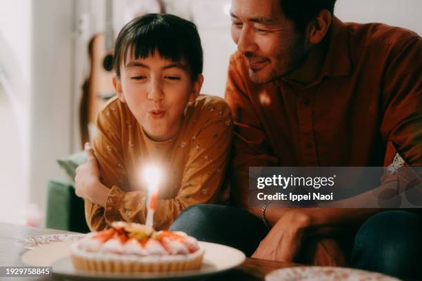 young girl blowing birthday candles on cake - parents children blow candles asians stock pictures, royalty-free photos & images