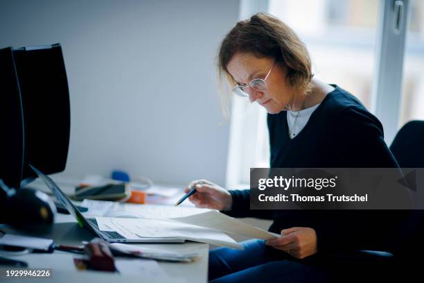 Symbolic photo on the topic of analog organization of papers. A woman sits at a desk in the office and works with documents on January 16, 2024 in...