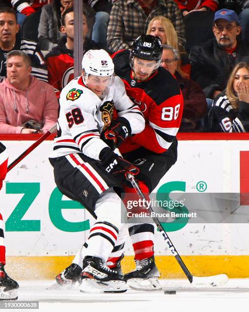 MacKenzie Entwistle of the Chicago Blackhawks skates against Kevin Bahl of the New Jersey Devils at Prudential Center on January 05, 2024 in Newark,...