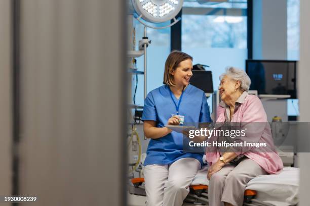 portrait of caring nurse and senior patient talking in hospital examination room. emotional support for elderly woman. - female nurse stock pictures, royalty-free photos & images