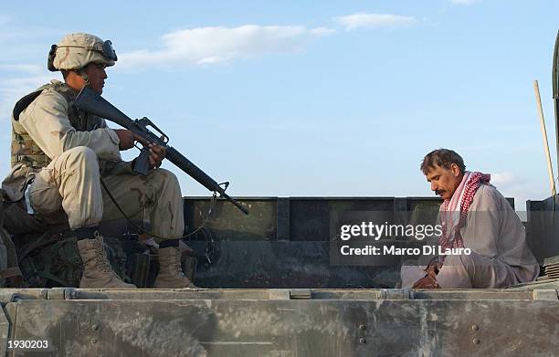 Marine guards an Iraqi prisoner of war in the main Square of Tikrit, April 14, 2003 some175 kilometers - just over 100 miles - north of the capital...