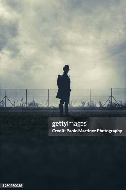 silhouette gangster standing on road - gangster stock pictures, royalty-free photos & images