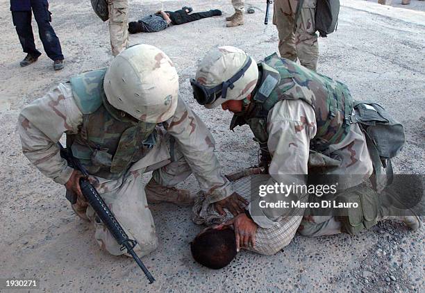 Marines arrest an Iraqi prisoner of war in the main Square of Tikrit April 14, 2003 some175 kilometers - just over 100 miles - north of the capital...