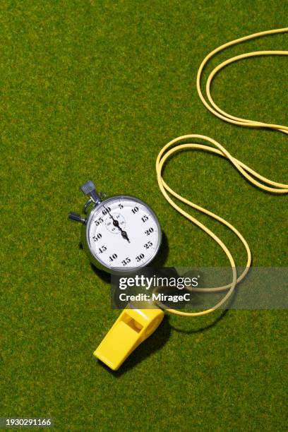 yellow whistle with stopwatch on green turf background - spielregeln stock-fotos und bilder