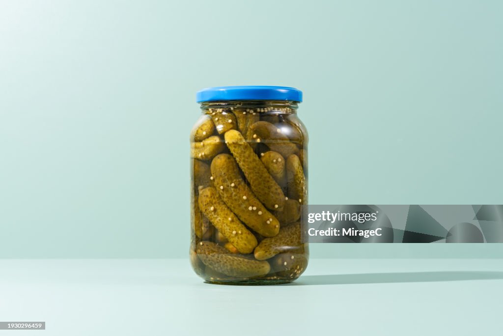 Pickles, Preserved Gherkins in Glass Jar on Green Background