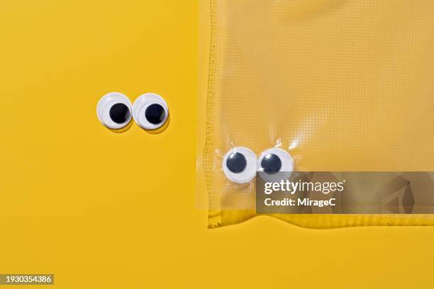 googly eyes trapped in a plastic bag - access control cartoon foto e immagini stock