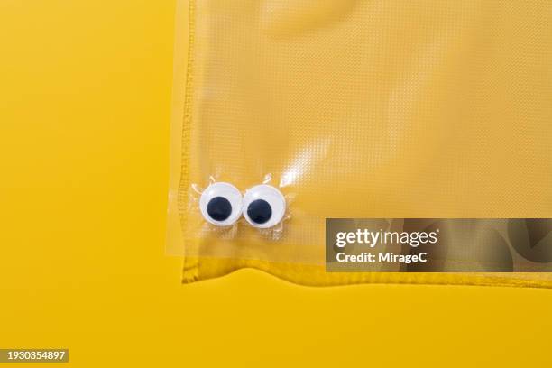 googly eyes trapped in a plastic bag - access control cartoon foto e immagini stock