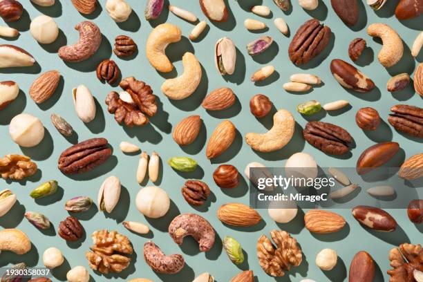various nuts flat lay on green background - pecan stock pictures, royalty-free photos & images