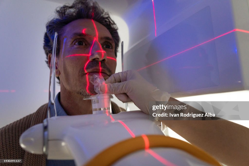 Mature man places dental x-ray head on x-ray machine
