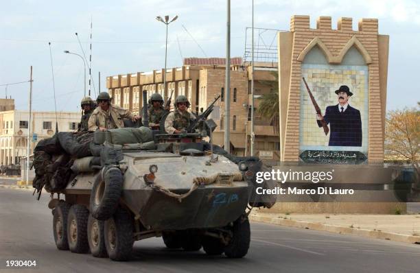 Marines pass a Saddam Hussein portrait as they operate a light armored vehicle April 14, 2003 in the center of Tikrit which is located approximately...