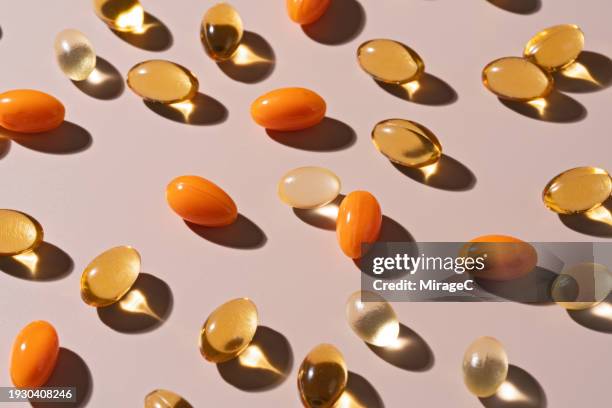 various of soft gel capsule pills on beige background - cod liver oil stock pictures, royalty-free photos & images