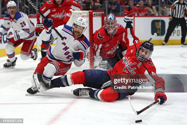 Tom Wilson of the Washington Capitals tries to handle the puck in front of Vincent Trocheck of the New York Rangers during the third period at...