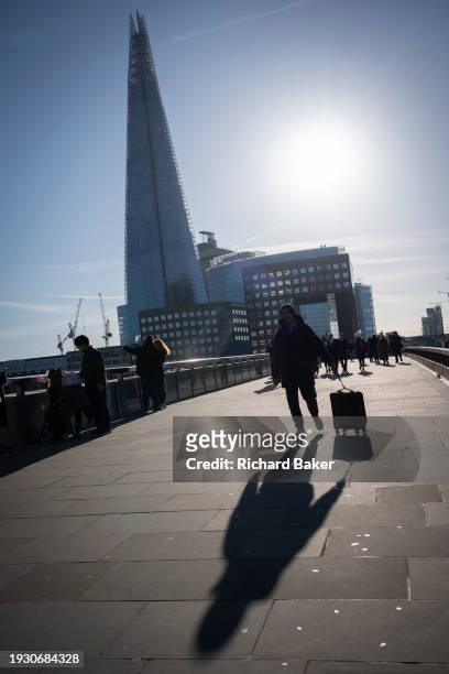 Person crosses Lonon Bridge pulling a piece of baggage towards the City of London, the capital's financial district, on 16th January 2024, in London,...