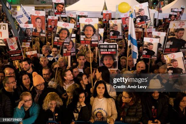 People hold photos of hostages during a rally to mark 100 days of captivity for hostages by Hamas in Gaza on January 13, 2024 in Tel Aviv, Israel....