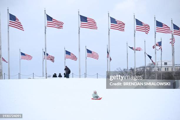 Child rides a sled near the Washington Monument in Washington, DC, on January 16, 2024. The Washington DC metro region received between 2 and 4...