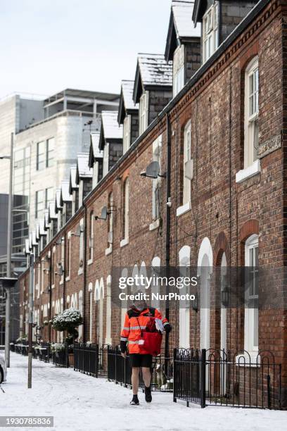 Postman is wearing shorts in Ancoats after heavy snowfall in Manchester city centre on January 16, 2024.