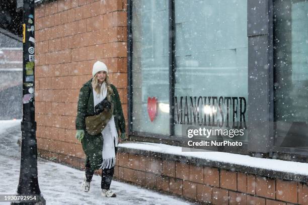 Woman is carrying her dog after heavy snowfall in Manchester City Centre, on January 16, 2024.