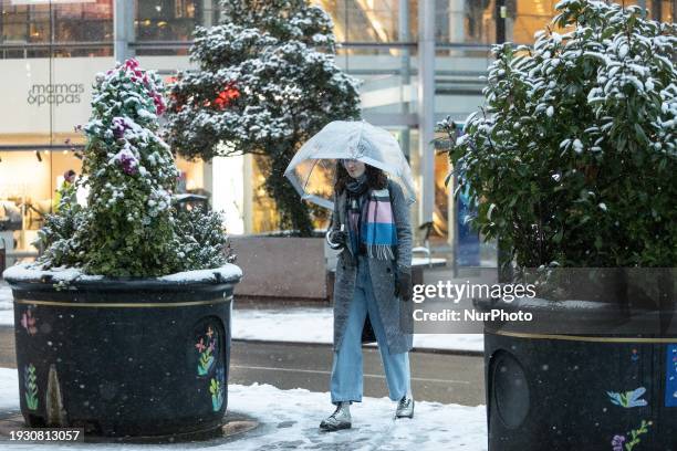 Woman is wrapping up warm after heavy snowfall in Manchester, United Kingdom, on January 16, 2024.