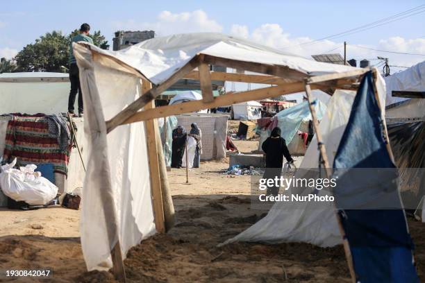 Displaced Palestinians are gathering outside makeshift shelters in Deir al-Balah, in the central Gaza Strip, on January 15 amid ongoing battles...