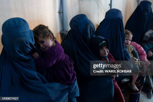 This photograph taken on January 9, 2024 shows Afghan burqa-clad women and children refugees deported from Pakistan, in a nutrition ward at the...