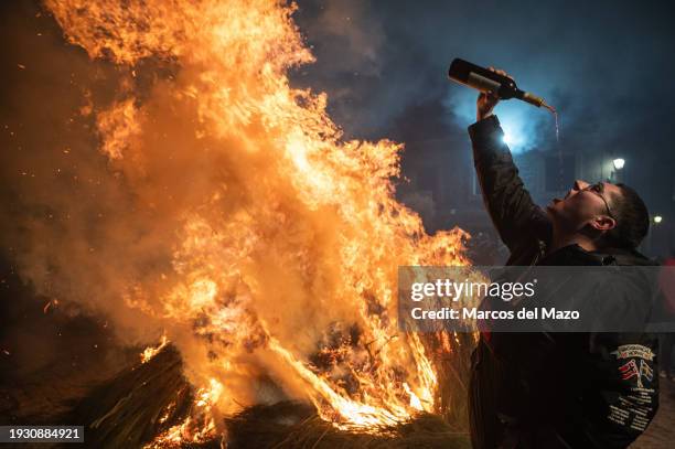 Reveler drinks wine next to a bonfire during the traditional "Las Luminarias" celebration. Each year, horse riders jump over bonfires during the...