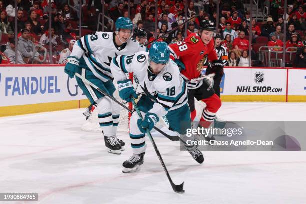 Filip Zadina of the San Jose Sharks grabs the puck ahead of teammate Henry Thrun and MacKenzie Entwistle of the Chicago Blackhawks in the second...