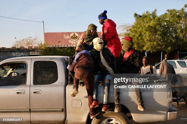 Migrants sit in the back of a pickup a few minutes before travelling to the Libyan border in Agadez on January 2, 2024. Agadez, nicknamed the...