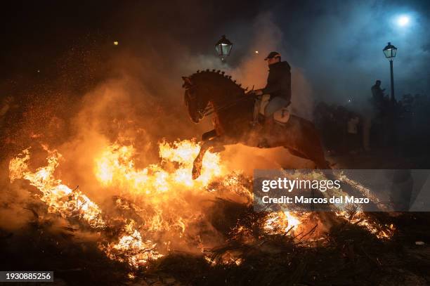 Horse rider jumps over a bonfire during the traditional "Las Luminarias" celebration. Each year, horse riders jump over bonfires during the...