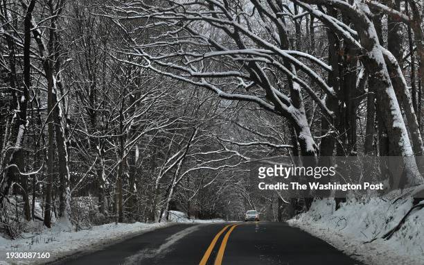 Snow covered trees create a tunnel effect on Brink Road in Germantown, Maryland on January 16, 2024. Snow and colder temperatures impacted the area...