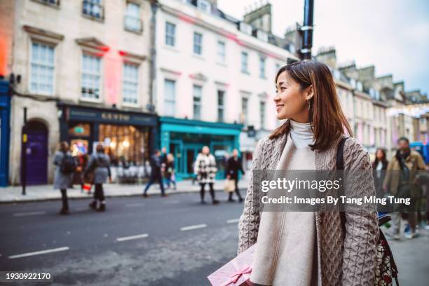 beautiful asian woman holding a gift box while shopping in high street of a town - calle principal fotografías e imágenes de stock