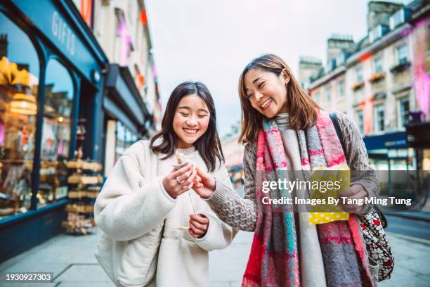 mom & daughter shopping for souvenir while exploring in a town during travelling - geschenktüte einwickelpapier stock-fotos und bilder