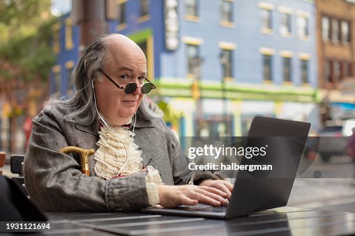 Benjamin Franklin Impersonator Typing on his Laptop While Looking at Camera with Eyebrow Raised