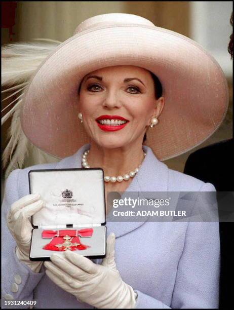 Dynasty actress Joan Collins shows off the OBE presented to her by the Queen at today's Buckingham Palace investiture.