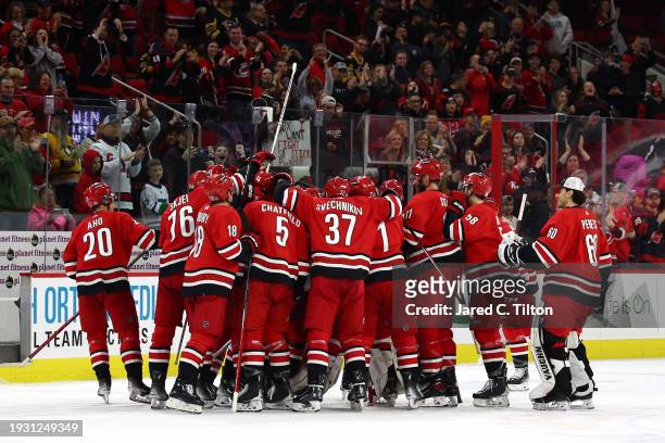 The Carolina Hurricanes celebrate their 3-2 overtime victory over the Pittsburgh Penguins at PNC Arena on January 13, 2024 in Raleigh, North Carolina.
