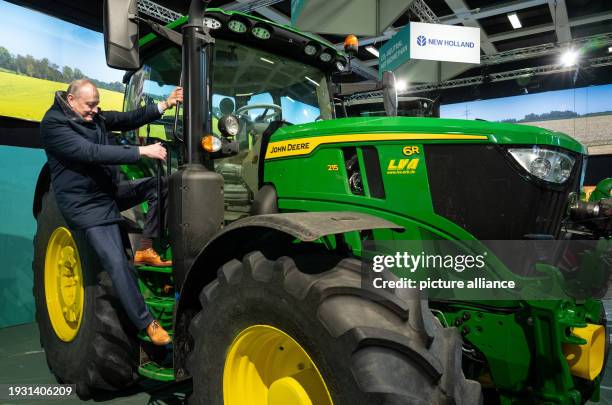 January 2024, Berlin: Joachim Rukwied, President of the German Farmers' Association, climbs onto a John Deere tractor during a press event organized...