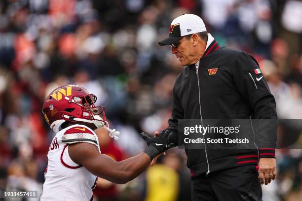 Brian Robinson Jr. #8 and Head coach Ron Rivera of the Washington Commanders interact before the game against the Dallas Cowboys at FedExField on...