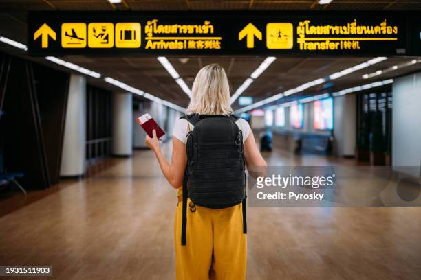 a woman at the airport holding a passport with a boarding pass - boarding pass stock-fotos und bilder