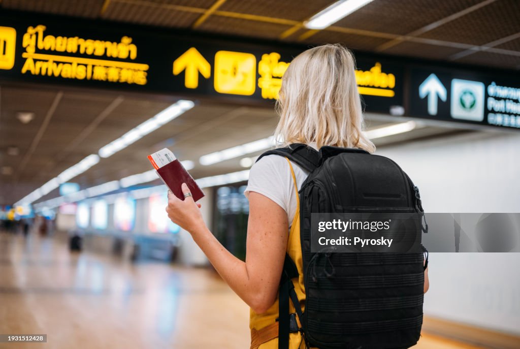 A woman at the airport holding a passport with a boarding pass