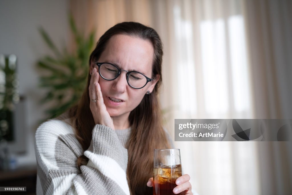 Woman with ice tea or soda drink suffering from tooth sensitivity