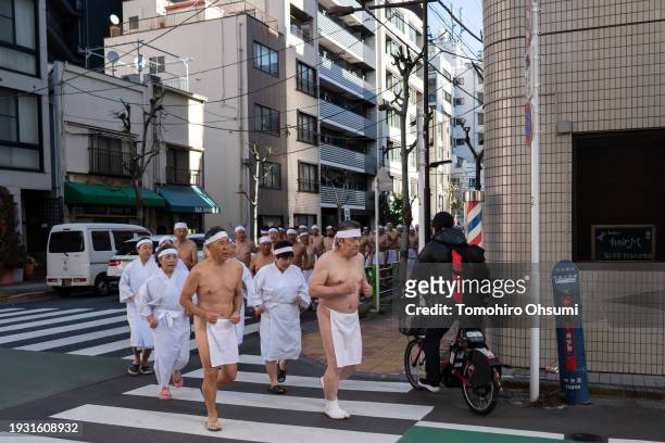 Participants run outside Teppozu Inari Shrine prior to bathing in ice-cold water during a Shinto ritual on January 14, 2024 in Tokyo, Japan. The...