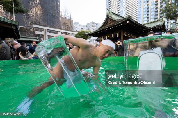 Participant holds an ice block in ice-cold water during a Shinto ritual at Teppozu Inari Shrine on January 14, 2024 in Tokyo, Japan. The annual new...