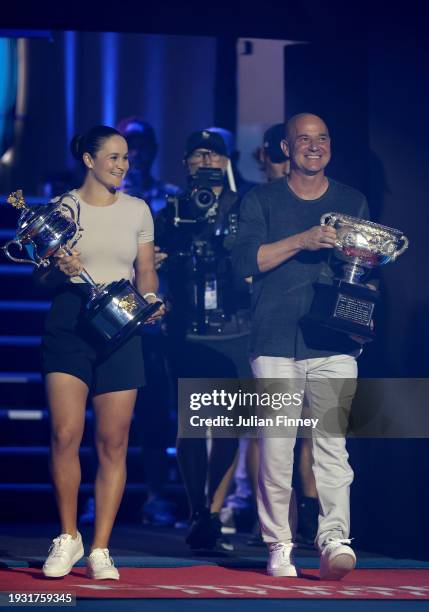 Ash Barty walks with the Daphne Akhurst Memorial Cup and Andre Agassi walks the Norman Brookes Challenge Cup onto Rod Laver Arena during day one of...