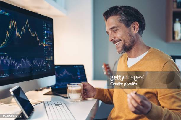 lächelnder trader schaut sich börsengrafiken an - roi stock-fotos und bilder