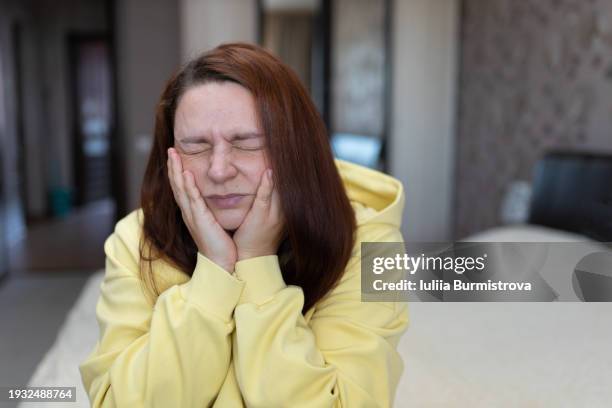 a woman with her eyes closed and suffering from toothache - gingivitis stock-fotos und bilder