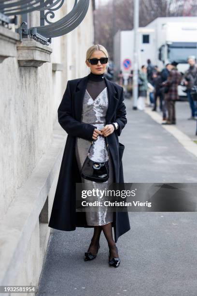 Caroline Caro Daur wears silver sequined dress, black coat, tights, bag, heels, turtleneck, sunglasses outside Prada during the Milan Fashion Week -...