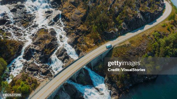 aerial view of camper van driving idyllic mountain road above scenic waterfall in norway - green bridge over trees stock pictures, royalty-free photos & images